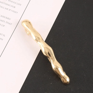 Makro-Detail der glänzend goldenen Wellen-Haarklammer mit polierter Oberfläche und Feder