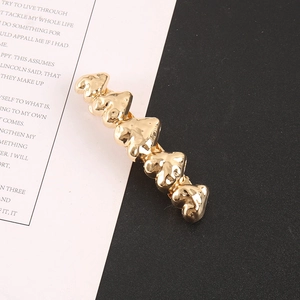 Détail d'une barrette en alliage doré avec texture de cœur irrégulière effet lave