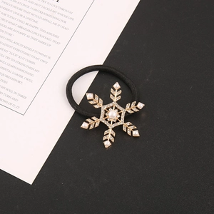 Detailed view of a gold snowflake hair tie with central pearl and sparkling rhinestones