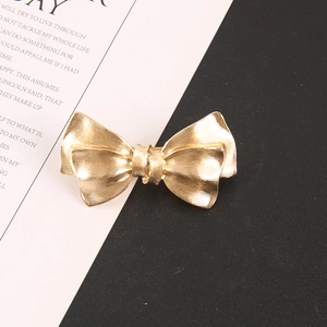 Detail showing the pleated golden metal texture and bow-knot design of the hair clip