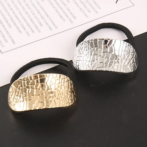 Détail de poignets métalliques à texture géométrique en or et argent sur des élastiques