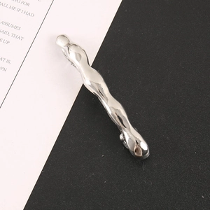 Makro-Detail einer wellenförmigen silbernen Haarklammer mit poliertem Spiegel-Finish