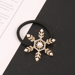 Detailed close-up of golden snowflake hair tie with white pearls and sparkling rhinestones