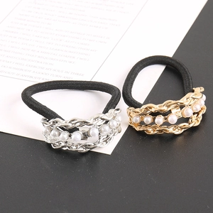 Detail of black elastic hair ties with gold and silver chains and faux pearls