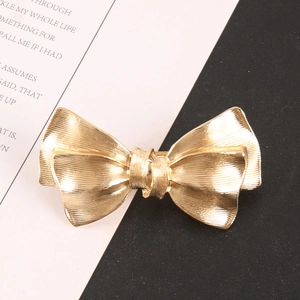 Elegant gold metal bow hair claw with brushed texture for women on a monochrome background