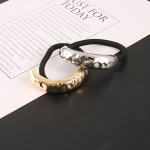 Close-up of gold and silver hair ties with hammered metal texture on minimal background