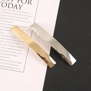 Close-up of minimalist rectangular metal hair clips in gold and silver mirror finish