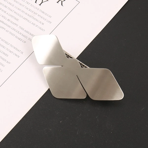 Macro detail of geometric silver bird-shaped hair clip with a brushed matte finish surface