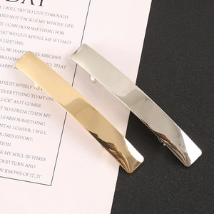 Close-up of minimalist metal hair clips in gold and silver with a polished mirror finish