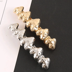 Détail de barrettes à cheveux à motifs cœurs gaufrés en finitions or et argent