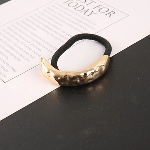 Detail of minimalist black hair tie featuring a golden hammer-textured metal buckle