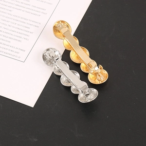 Close-up of gold and silver textured metal hair clips with spring mechanism details