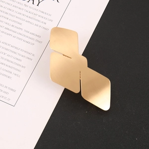 Close-up of geometric bird-shaped hair clip in matte gold finish on creative background