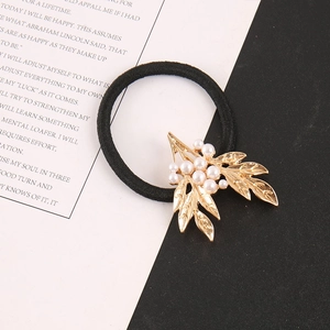 Détail d'un chouchou doré orné de perles blanches et d'un élastique noir robuste