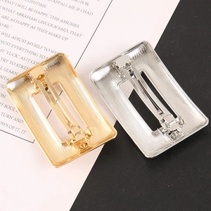 Détail de barrettes rectangulaires en alliage avec texture brossée verticale dorée et argent
