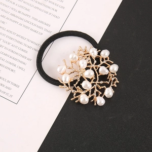 Detailed close-up of golden coral-shaped alloy hair tie with pearls and rhinestones