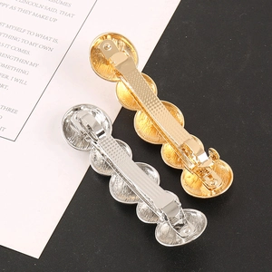 Close-up of gold and silver hair clips with radial striped texture and spring design