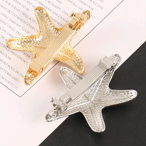 Dettaglio dei fermagli per capelli a stella marina in oro e argento con texture naturale