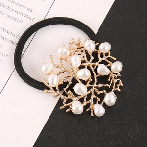 Close-up of pearl hair tie with gold coral alloy detail and crystals on elastic band