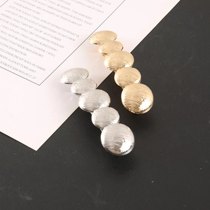 Detail of gold and silver textured metal hair clips with a pleated round disc design