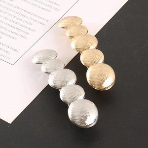 Macro detail of textured metallic hair clips in gold and silver plating with ripple finish