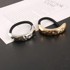Detailed close-up of gold and silver hammered metal charms on black elastic hair ties