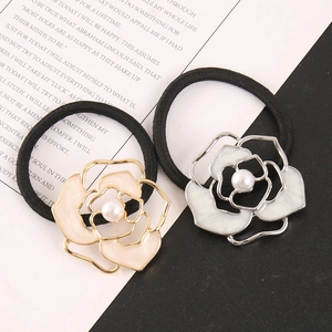 Detail of camellia hair ties with faux pearls and enamel petals on black elastic bands