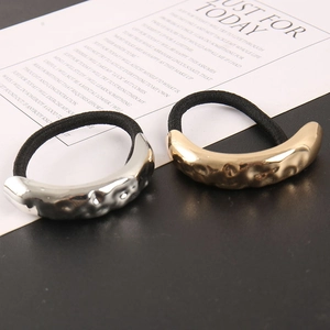 Detail showing textured gold and silver crescent hair ties on a minimalist backdrop