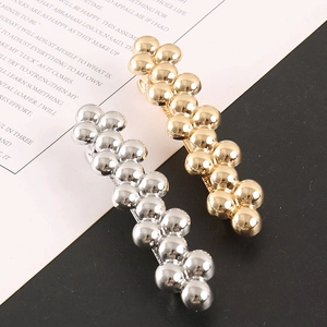 Detailed close-up of beaded hair clips with polished metallic gold and silver spheres