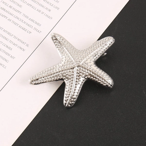 Dettaglio spilla a stella marina argento con perline metalliche e chiusura su sfondo nero