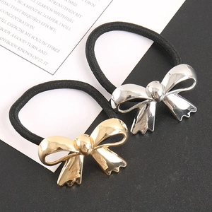 Detail of gold and silver bow ponytail holders with polished metallic finish and wavy edges