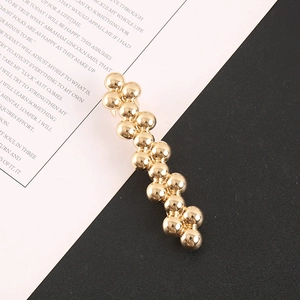 Detailed view of the layered gold metal beads on a sleek minimalist fashion hair clip