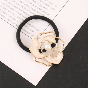 Detail of elegant black hair tie with hollow gold-edged camellia flower and pearl