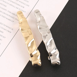 Close-up of gold and silver hair clips with irregular liquid metal texture and high shine