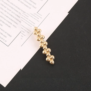 Macro detail of high-shine gold beaded barrette with minimalist metal spheres design