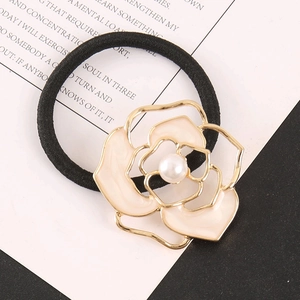 Detail of pink camellia hair tie with gold metal edge and pearl center on magazine
