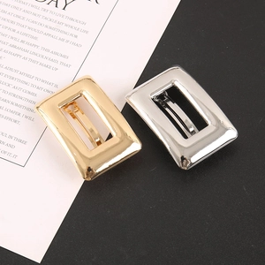 Détail de barrettes carrées évidées en métal doré et argenté avec fini poli miroir