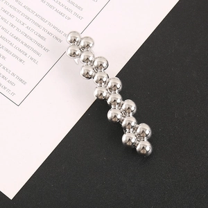 French minimalist silver beaded metal hair clip with polished finish on magazine background