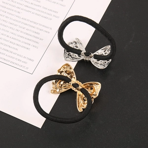 Detailed macro view of gold and silver metal bow hair ties with embossed textures