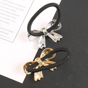 Detail view of gold and silver metallic bow hair ties on minimalist black elastic bands