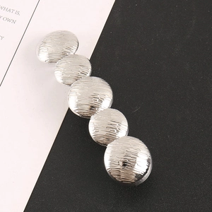 Silver metallic hair clip with pleated circular texture design on a minimal background