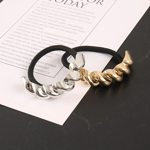 Detailsicht auf elastische Haargummis mit spiralförmigen Metallakzenten in Gold und Silber