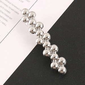 Detail view of silver beaded hair clip with metallic spheres on a magazine background