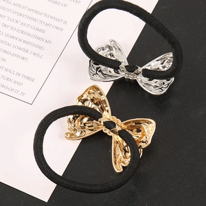 Detail of gold and silver butterfly hair ties with hollow metal charms on black elastic