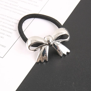 Close-up of a silver metal bow pendant on a high-elasticity black hair tie