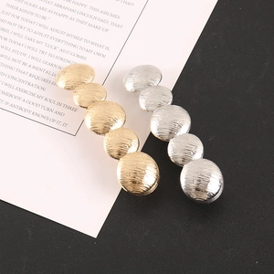 Macro shot of gold and silver hair clips featuring five hammered texture metal discs