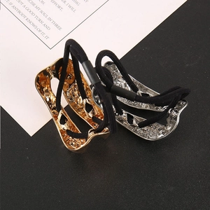 Dettaglio di piastre metalliche martellate irregolari in oro e argento su elastici neri