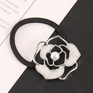 Close-up of elegant hollow camellia hair tie with white enamel petals and central pearl
