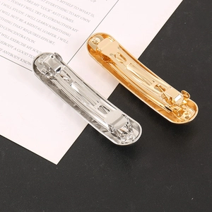Detail view of gold and silver oval alloy hair barrettes with metal spring clip back