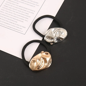 Close-up of gold and silver irregular metallic textured charms on black elastic hair ties
